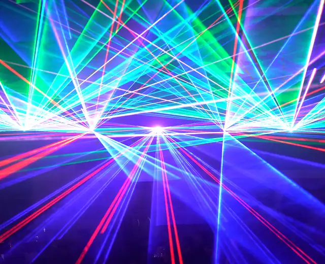 Bunter Laser-Tunnel in Cyan, Magenta und Grün über rotem Strahlenteppich in einer Halle mit Besuchern