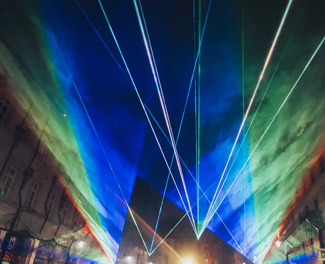 Farbige Laserflächen in Grün, Gelb, Rot und Blau fegen über die Altstadtgasse in Konstanz, das Publikum filmt mit Handys